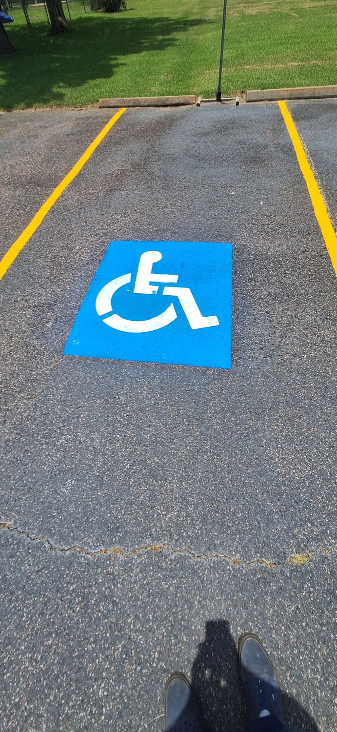 Close view of a blue and white accessible parking symbol between yellow stall lines