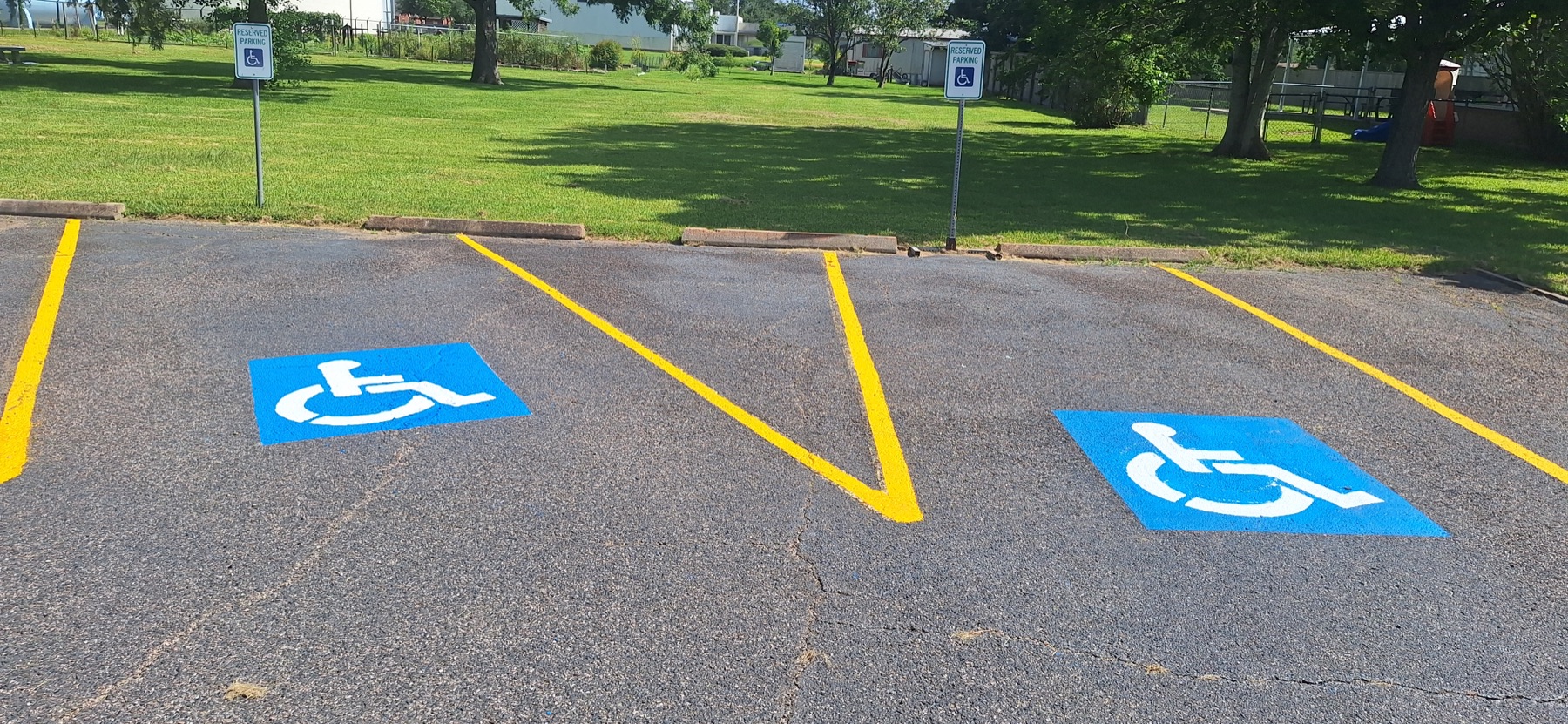 Two refreshed ADA parking spaces with blue accessibility symbols and yellow access aisle markings